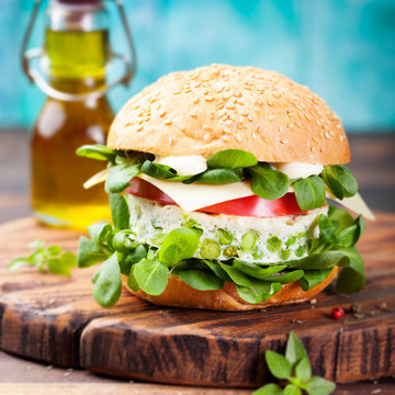 Vegetarian burger with egg and pea patty, fresh salad tomato.