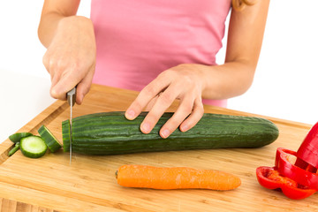 Woman cutting cucumber for salad