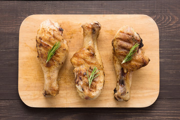 Grilled chicken drumstick and lemon on wooden background