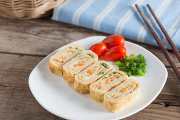 Eggs roll with carrot and onion on white plate. Selective focus.