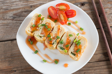 Eggs roll with carrot and onion on white plate. Top view.
