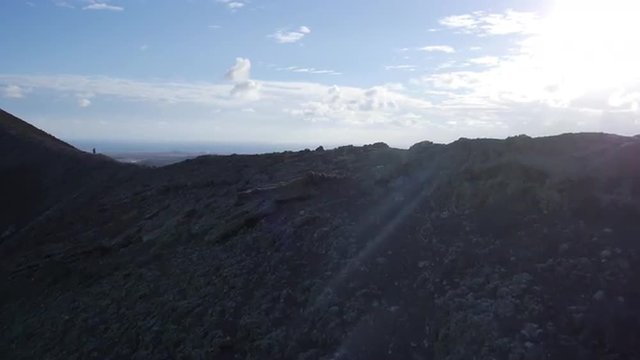 AERIAL: Man running on a volcanic crater