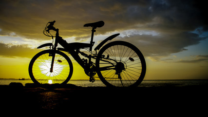 Silhouette of mountain bike with sunset sky at sea