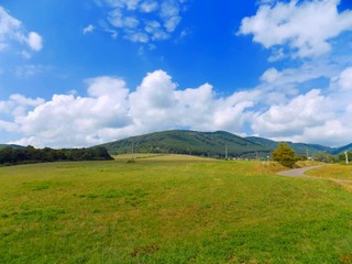 Meadow, asphalt road, hills and sky