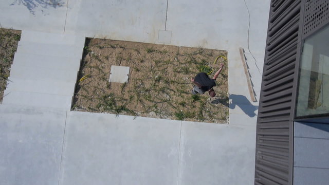 AERIAL: Skateboarder jumping over the lawn
