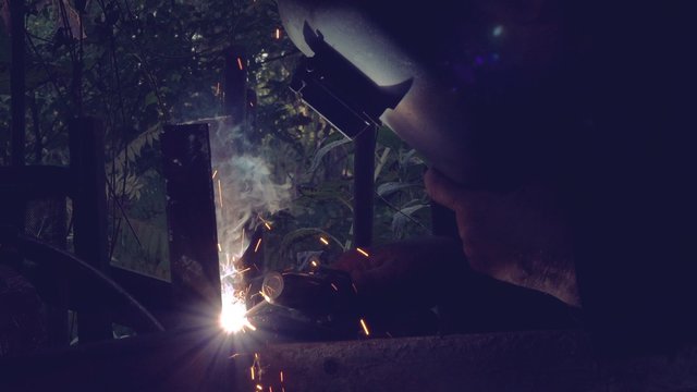 Shielded metal arc welding in workshop, male welder using electrode to melt the metal at the welding point.