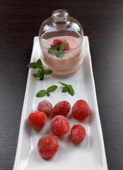 Pudding with strawberry frozen strawberry and mint cream bowls in glass, on a white plate