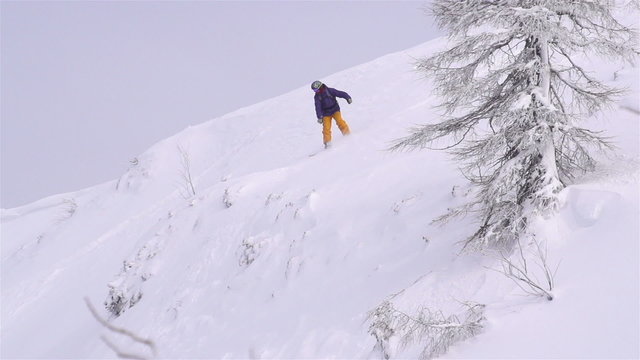 SLOW MOTION: snowboarder jumping over a cliff