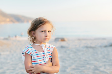 Adorable happy smiling little girl with curly hair on beach vaca