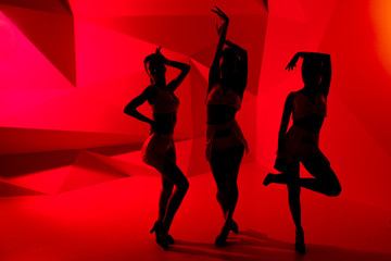 Silhouettes of three slim posturing girls