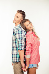 Happy couple in love holding hands standing back to back