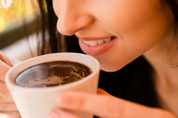 Charming young woman enjoying aroma coffee in cafe