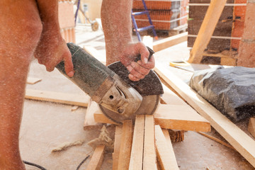 Worker cutting wood with angle grinder
