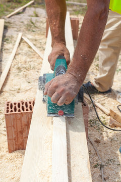 Carpenter working with electric planer