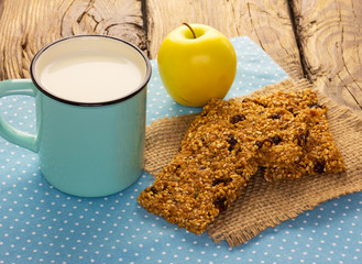 Granola bars with cup of milk on wooden table