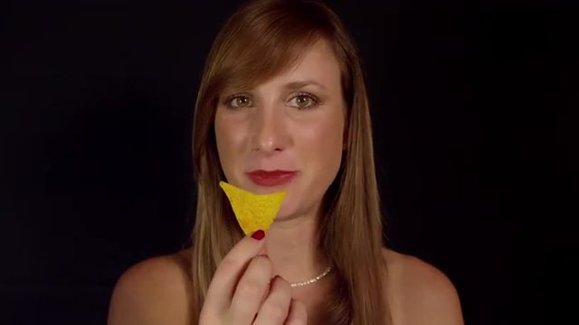 SLOW MOTION: Smiling young woman eating tortilla chips