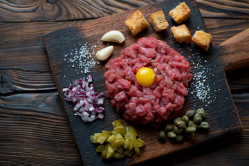 Beef tartare on a rustic wooden chopping board, above view