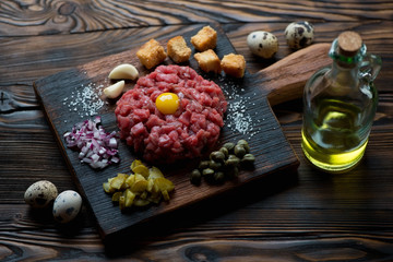 Beef tartare with egg yolk, capers, sliced pickles and onion