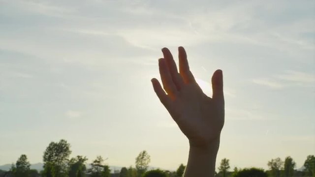 SLOW MOTION CLOSE UP: Waving hand over the sun