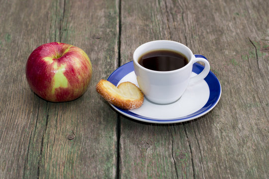 coffee on a saucer, cookies and one apple, on a wooden table