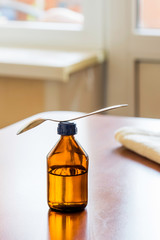 Cough Syrup Bottle With Spoon Close tothe Window