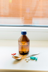 Cough Syrup Bottle With Spoon Close tothe Window