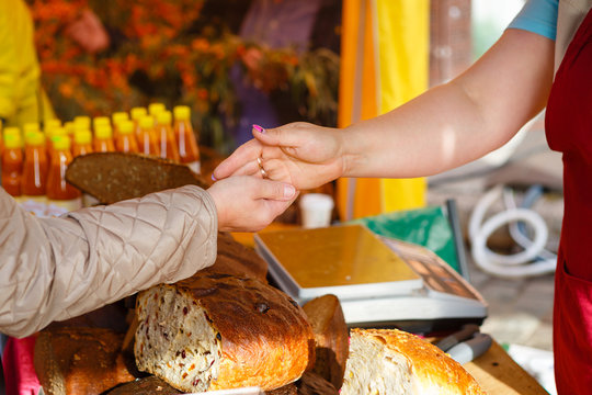 Hands of woman paying cash with Euro money for fresh bread at farmer's seasonal market in europe