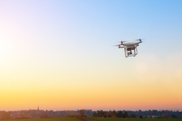 Unbemannte RC Drohne fliegt auf einem freien Feld bei Sonnenuntergang