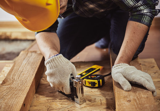 Young man builder in workwear repairing wooden furniture in a house. Concept of renovation and woodwork. 