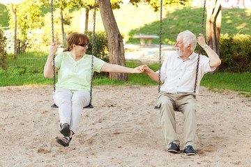 Senior couple swinging in the park