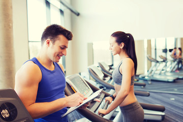 happy woman with trainer on treadmill in gym