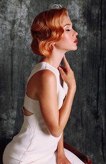 Naklejka premium beautiful young woman with short red hair in retro style,wears elegant white dress