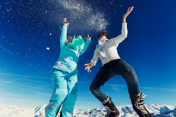 woman and man in ski suit jump on the background of the Alps Cou