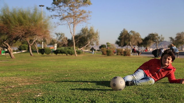 Young boy kicking ball in the grass outdoors