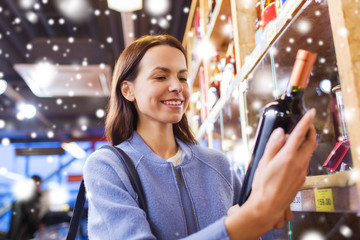 happy woman choosing and buying wine in market