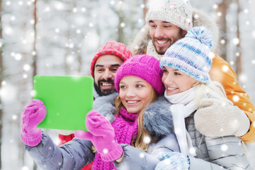 Obraz premium smiling friends with tablet pc in winter forest