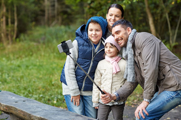 happy family with smartphone selfie stick at camp