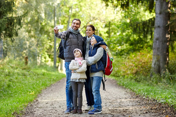 Naklejka na ściany i meble family taking selfie with smartphone in woods