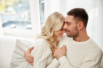 happy couple covered with plaid on sofa at home