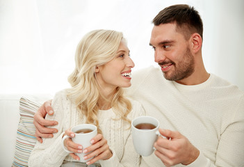 Obraz na płótnie Canvas happy couple with cups drinking tea at home