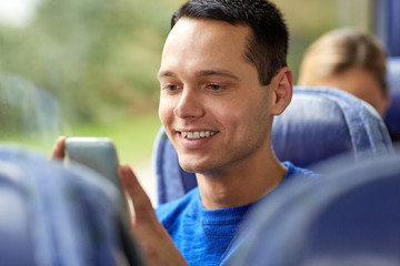 happy man sitting in travel bus with smartphone
