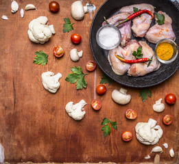 Raw chicken wings with salt and pepper tomorrow spices on an old cast-iron skillet mushrooms Cauliflower Cherry tomatoes and parsley on wooden rustic background top view