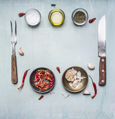 ingredients for cooking, seasoning, oil, knife, fork, garlic, hot red pepper, lined frame on wooden rustic background top view close up with text area