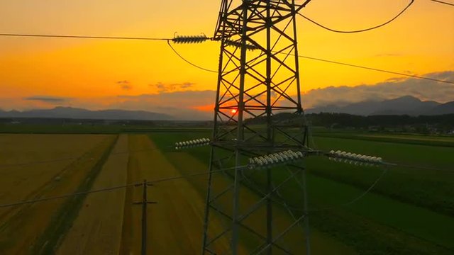 AERIAL: Flying up the high voltage electricity tower at sunset