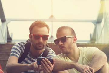 Young urban guys using a smartphone outdoors.