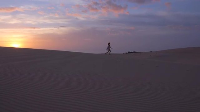 AERIAL: Female in a desert at sunrise