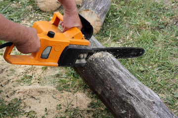 Worker cuts a beam by electric chain saw