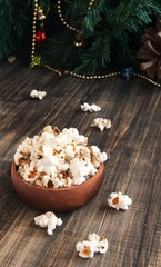 popcorn in a wooden plate on the background of Christmas trees