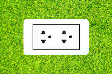 Electric power receptacle on a green grass surface background