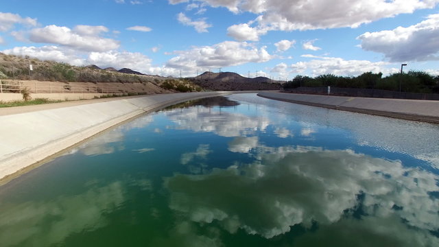 Aerial above canal water with mountain background